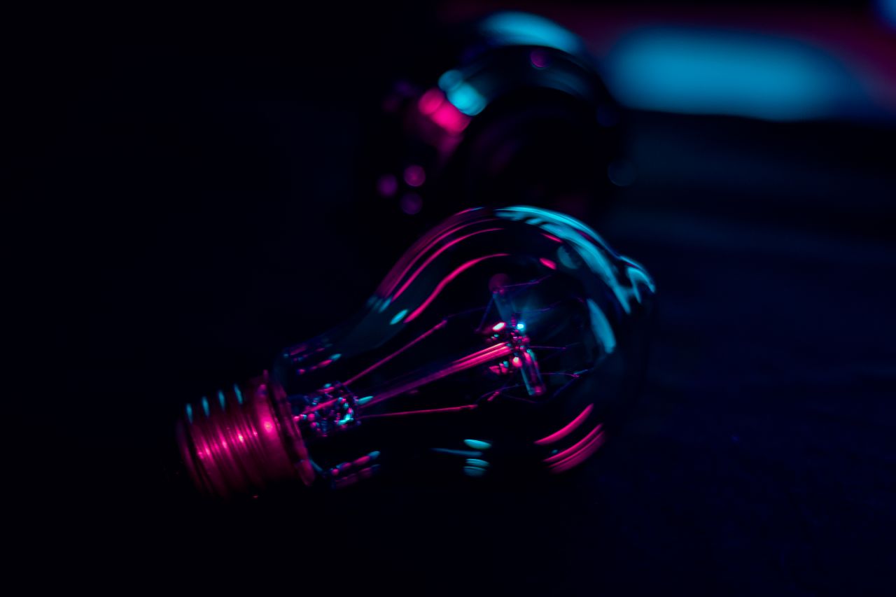 heros-img Dramatic close-up of a light bulb illuminated by vibrant neon lighting, evoking a creative and technological ambiance.
