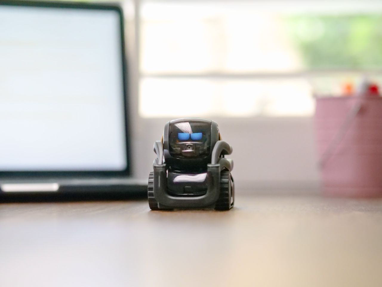 about-us-02 Small toy robot on a desk beside a laptop, symbolizing technology and innovation.
